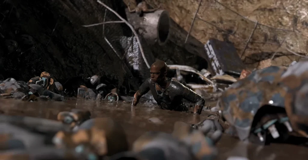 Man crawling through muddy wreckage in junkyard