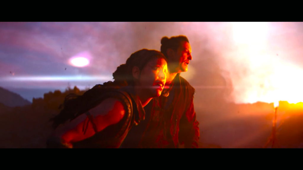 Two people look toward bright fire at night