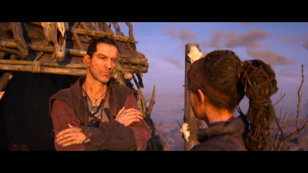 Two people talking beside wooden hut at sunset