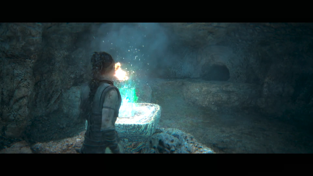 Senua watches blue-green flame in cave basin
