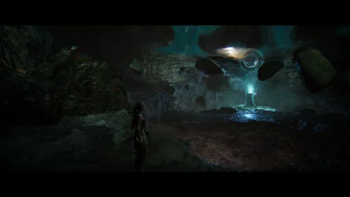 Person standing in dark cave near blue portal