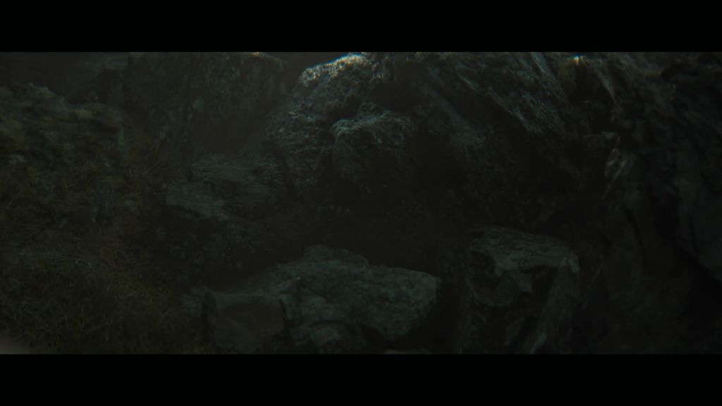 Sunlight beams over rocky hillside with grass