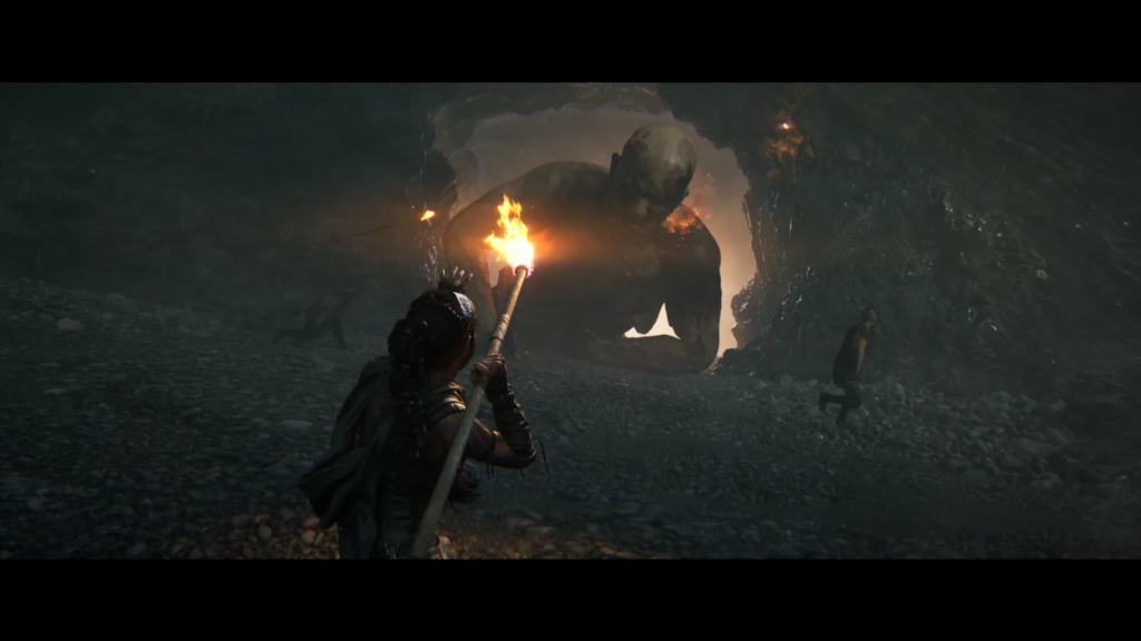 Warrior holds torch facing giant troll in cave