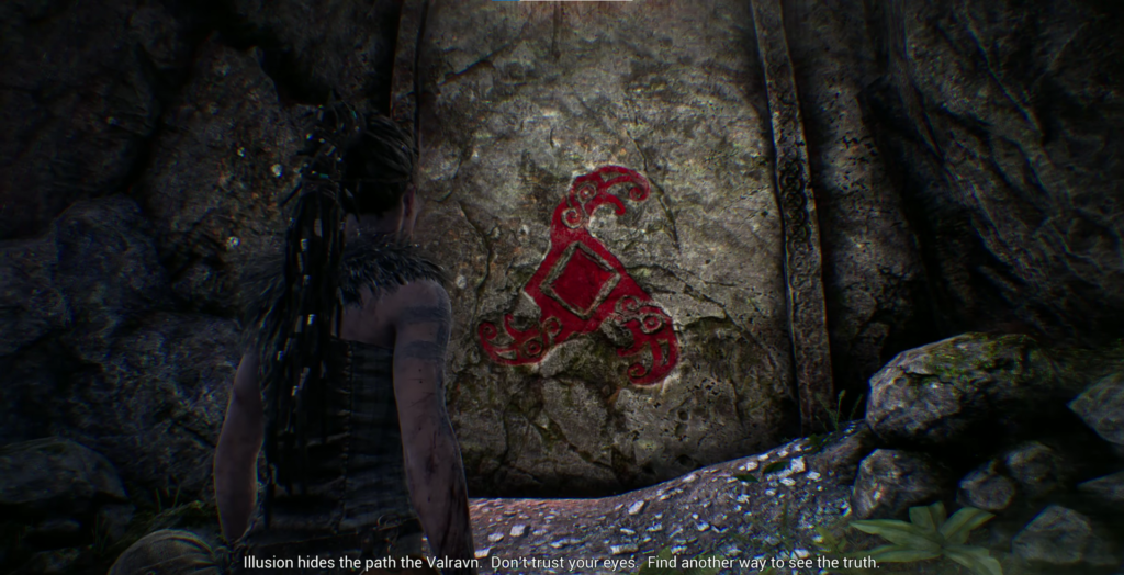 Senua faces red symbol on cave wall