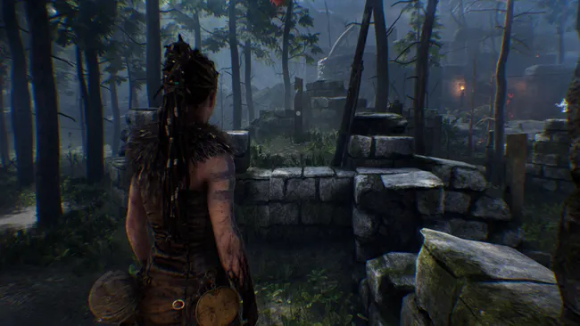 Woman stands by stone ruins in misty forest