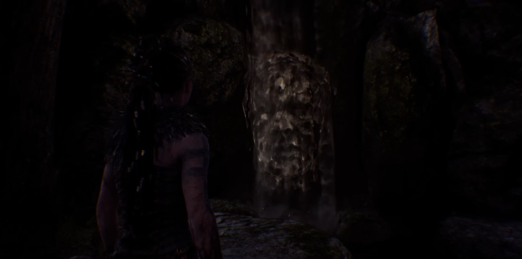 Senua stands near waterfall in dark cave