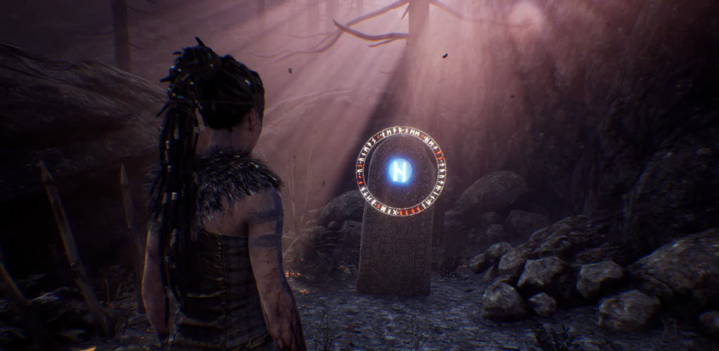 Senua watches glowing rune stone in dark cave