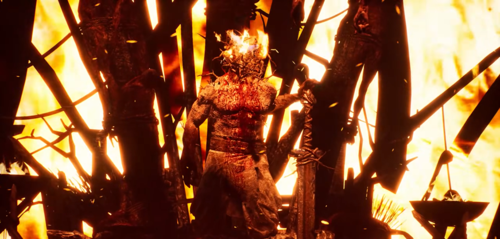 Burning armored figure stands amid flames and debris