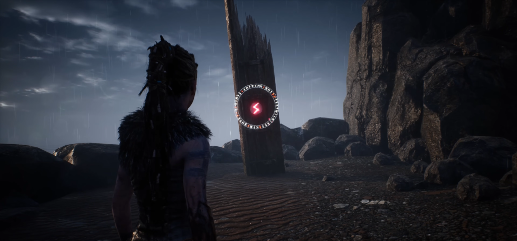 Senua watches glowing rune stone on rainy beach