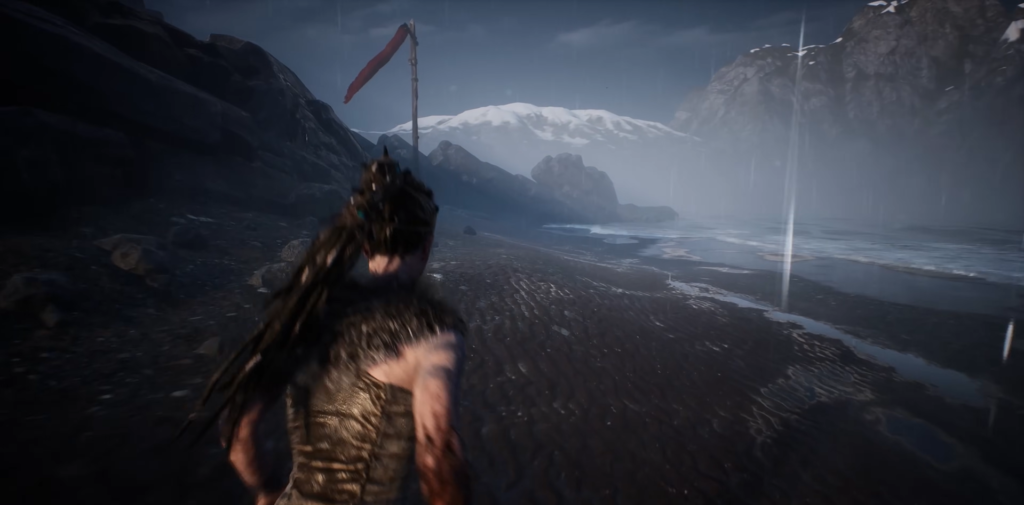 Senua runs along rainy beach near mountains in Hellblade