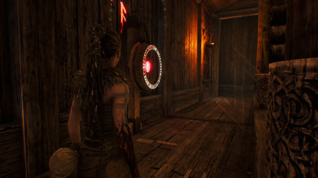 Senua in Hellblade stands near rune door in hallway