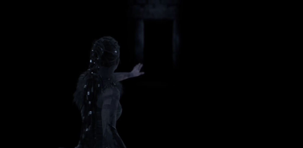 Девушка тянет руку к светящемуся проёму в темноте