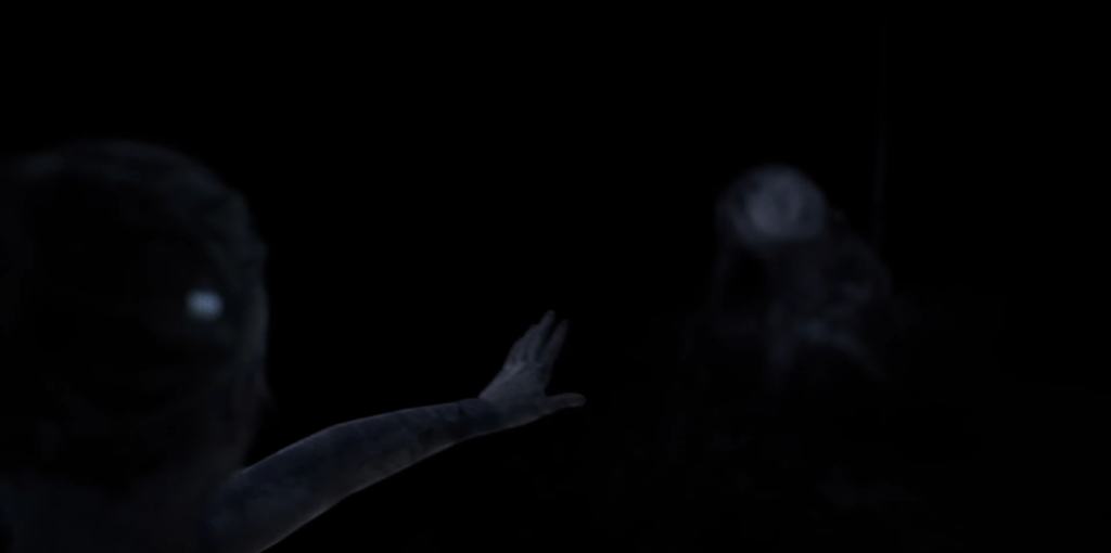 Рука тянется к размытым фигурам в темноте