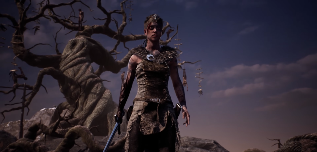 Senua stands holding sword beside twisted tree at dusk