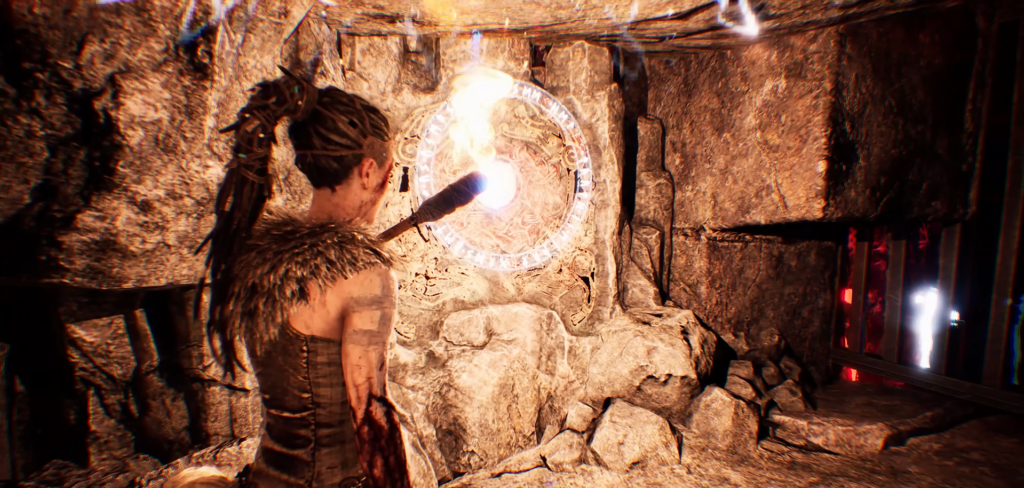 Senua touches glowing rune circle on cave wall