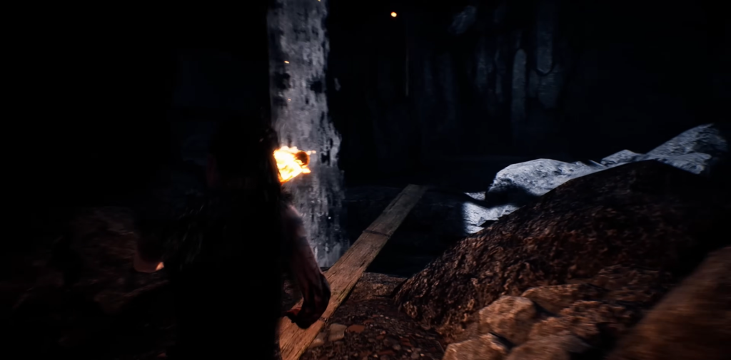 Person holding torch in dark cave tunnel