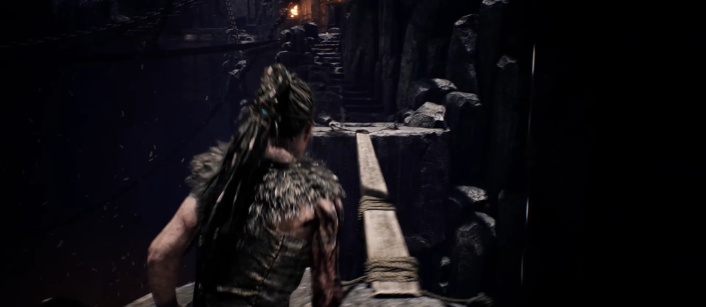 Senua runs across narrow bridge in dark ruins