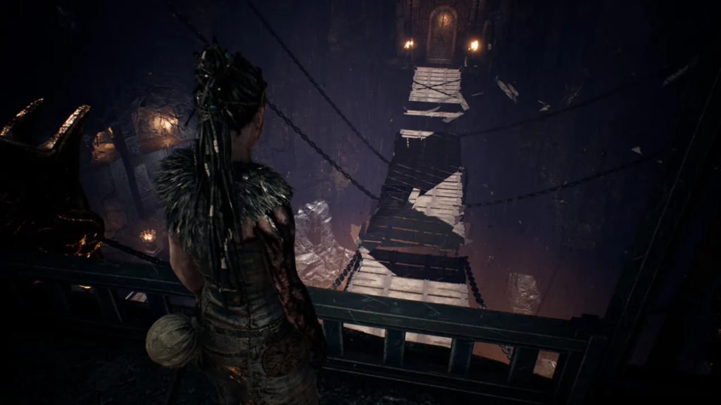 Senua looks over wooden bridge in dark cavern