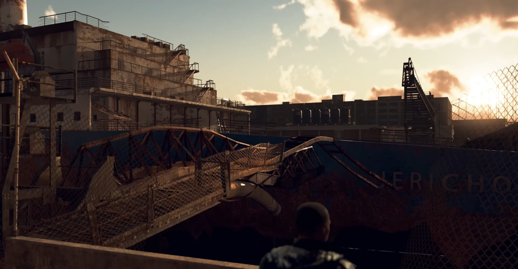 Person looking over fenced industrial site at sunset