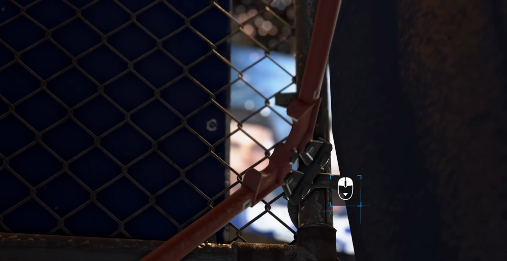 Hand holding red crowbar near chain-link fence