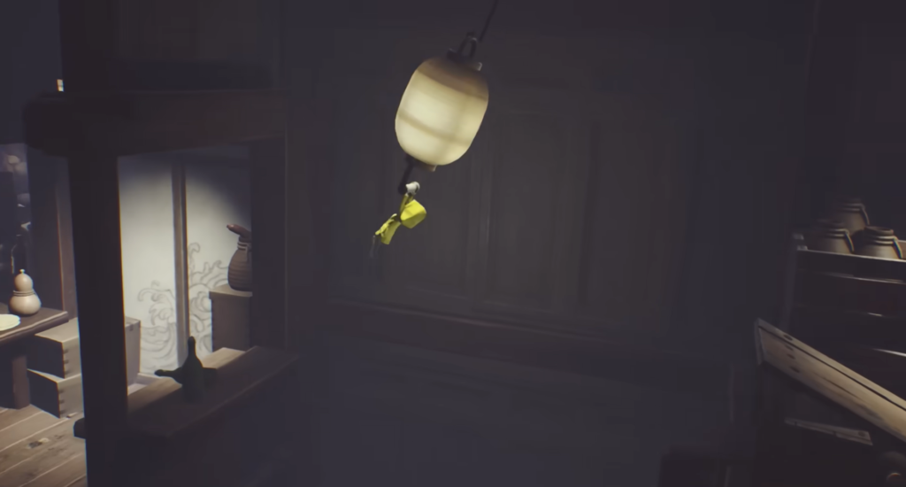 Six from Little Nightmares hanging from lantern indoors