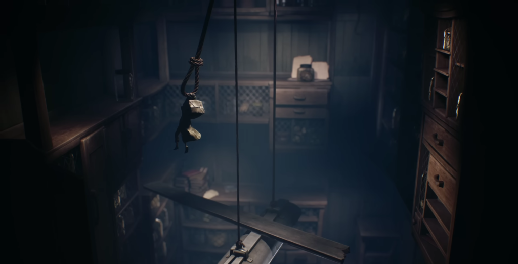 Small figure hanging from rope in dark room