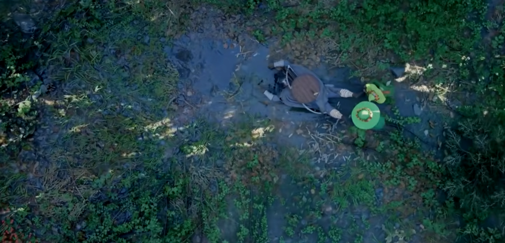 Two people lie beside wheelchair in forest clearing